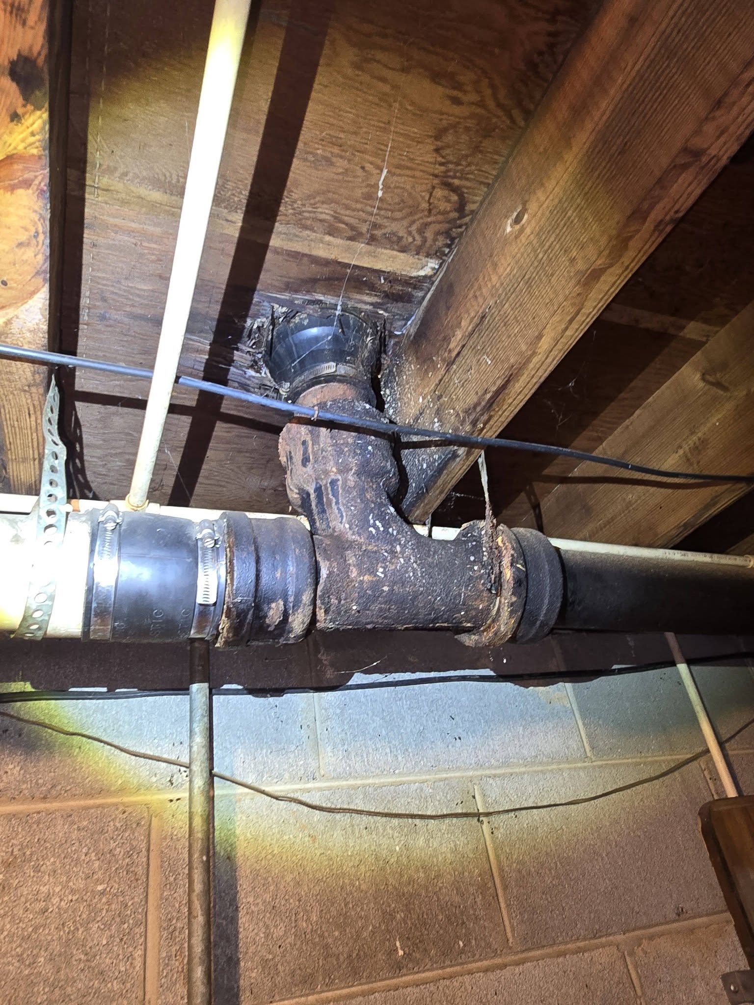 Corroded cast iron pipe in a crawlspace, photographed before repair